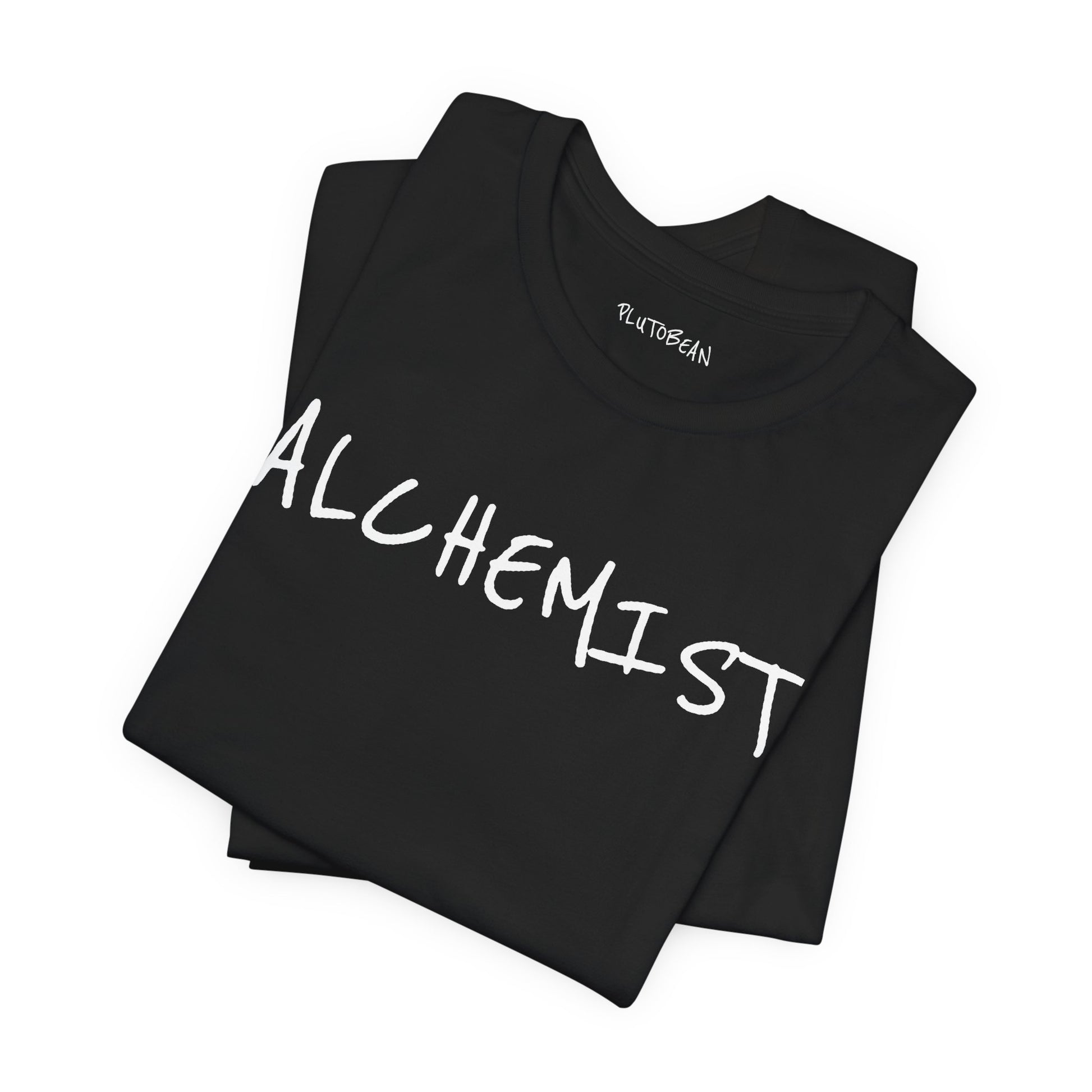 Folded black tee with bold handwritten “ALCHEMIST” wordmark in white